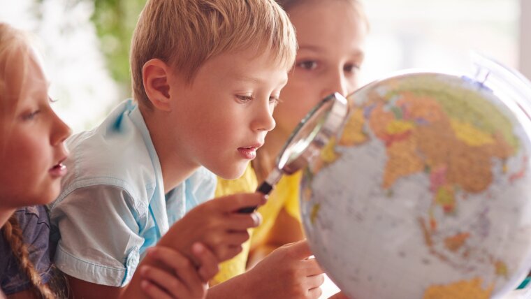 Kinder betrachten einen Globus