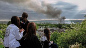 nach russischem Bombardement bobachten junge Frauen die aufsteigenden Rauchsäulen über Charkiw