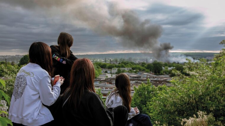 nach russischem Bombardement bobachten junge Frauen die aufsteigenden Rauchsäulen über Charkiw