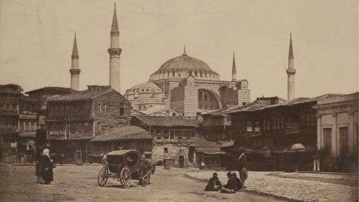 James Robertson (1813-1888): Konstantinopel (Istanbul), vor 1857, signiert: "Robertson", Salzpapierabzug vom Papiernegativ (?) 30,5 x 21,9 cm, InvNr. 0017.1. Der gebürtige Brite kam nach 1840 als Chefgraveur und Oberaufseher der osmanischen Münzstätte nach Konstantinopel. Er ist insbesondere durch seine Zusammenarbeit mit Felice Beato bekannt, mit dem er den Krim-Krieg dokumentierte. Robertson führte eine genaue Bildregie, die nichts dem Zufall überließ: hier die Hagia Sophia. Im Bild sind einiger Personen aufgrund der langen Belichtungszeit nur schemenhaft zu sehen, die Robertson für seine Aufnahme nicht arrangiert hatte.