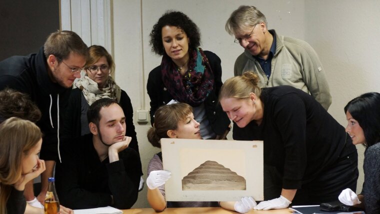 Studierende und Mitarbeiter betrachten ein archäologisches Fundstück